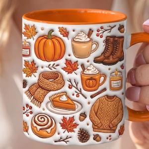 Op de afbeelding: Een witte keramische mok met een oranje binnenkant en handvat, voorzien van een herhalend patroon van herfstachtige illustraties waaronder pompoenen, oranje esdoornbladeren, bruine laarzen, gebreide sjaals, kaneelbroodjes, truien en kaarsen.