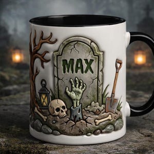 May include: White ceramic mug with a black interior and handle, featuring a spooky graveyard design. The design includes a tombstone with the name "MAX", a zombie hand, a skull, and a shovel. The mug is perfect for Halloween.