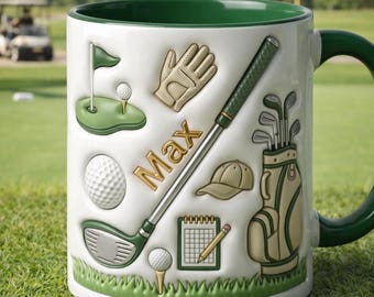 May include: White ceramic mug with a green interior and handle, decorated with golf-themed embossed images. Features a golf club, golf ball, glove, and the name "Max". The mug sits on a green grassy surface.