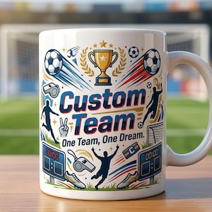 Puede incluir: Una taza de cerámica blanca con un gráfico colorido de temática futbolística. El diseño incluye un trofeo dorado, balones de fútbol, silbatos, marcadores y siluetas de jugadores. El texto dice Custom Team y One Team, One Dream en azul y negro.