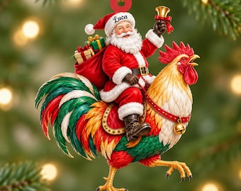 May include: A Christmas ornament featuring Santa Claus with a white beard and red suit riding a large rooster with colorful green, red, and yellow feathers. Santa holds a gold bell and carries a sack of gifts. The name Luca is printed on the hat.