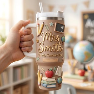 May include: A tan insulated tumbler with a white handle and lid, featuring raised school-themed icons including pencils, a chalkboard with A+, a ruler, a red apple, books, and a globe. The text reads Mrs. Smith and In My Teacher Era.