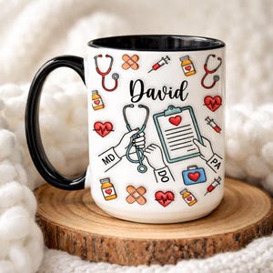 Puede incluir: Taza de cerámica blanca con asa y borde negros. Decorada con ilustraciones de temática médica, incluyendo estetoscopios, corazones, jeringas y vendas. El nombre "David" está escrito en negro.
