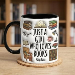 Pu&ograve; includere: Tazza in ceramica bianca con manico e interno neri. La tazza presenta illustrazioni di libri, occhiali e una poltrona da lettura. Il testo sulla tazza recita "JUST A GIRL WHO LOVES BOOKS" con il nome "Sophia" sotto.