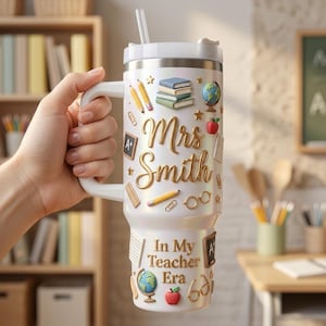 May include: A white iridescent tumbler with a handle and straw featuring gold script text that reads Mrs. Smith and In My Teacher Era. The design includes 3D-style graphics of books, a globe, pencils, an apple, eyeglasses, and small chalkboards.
