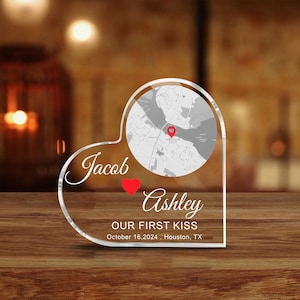 Könnte beinhalten: Herzförmiges Andenken aus klarem Acryl mit einer Kartengrafik und den Namen "Jacob" und "Ashley". Enthält den Text "OUR FIRST KISS" und das Datum 16. Oktober 2024 mit dem Ort Houston, TX.