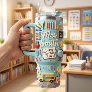 May include: A light blue insulated tumbler with a handle and straw, featuring 3D-style school-themed graphics including crayons, a ruler, a chalkboard, an apple, a globe, a school bus, and a notebook with the text "Mrs. Smith In My Teacher Era."
