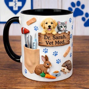 Puede incluir: Taza de cer&aacute;mica blanca con asa y borde negros, con un dise&ntilde;o 3D de un cachorro de golden retriever, un gato atigrado gris, un conejo marr&oacute;n y un erizo. La taza tiene el texto "Dr. Sarah, Vet Med." y huellas de patas.