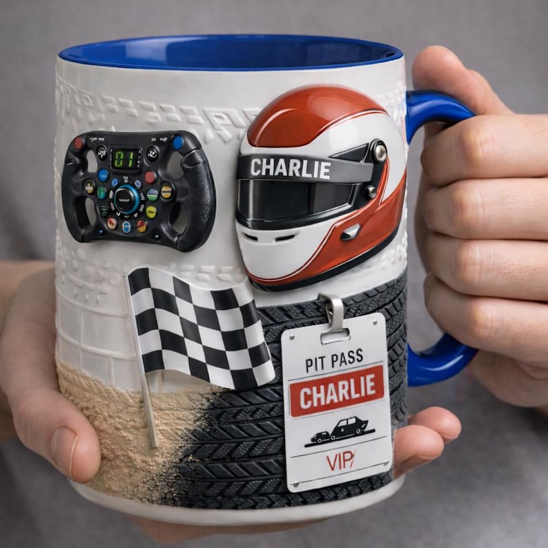 May include: White ceramic mug with a blue interior and handle, featuring racing-themed decorations. Includes a steering wheel, a red and white helmet with "CHARLIE" on it, a checkered flag, and a "PIT PASS CHARLIE VIP" tag.