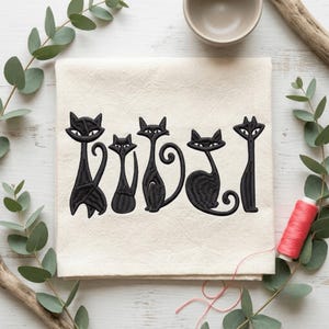 May include: A square off-white fabric cloth featuring an embroidered design of five stylized black cats in various poses. The cats have elongated bodies, pointed ears, and almond-shaped eyes, arranged in a horizontal row across the center of the cloth.