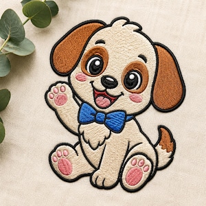 May include: An embroidered patch featuring a cartoon puppy with cream-colored fur, brown ears, and a blue bowtie. The puppy has large black eyes, a pink tongue, and pink paw pads. The design is outlined in black thread on a light fabric background.