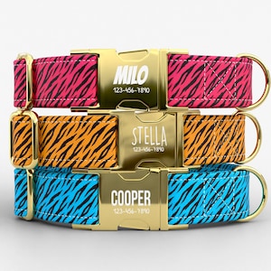 May include: Three personalized dog collars stacked. The collars feature a tiger stripe pattern in pink, orange, and blue. Each collar has a gold buckle with a name and phone number: Milo, Stella, and Cooper. The collars have gold hardware.