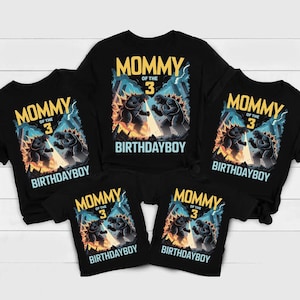 以下が含まれることがあります： ゴジラのような生き物と「MOMMY OF THE 3 BIRTHDAYBOY」の文字が描かれたグラフィックデザインの黒いTシャツ。さまざまなサイズがあり、家族の誕生日のお祝いに適しています。