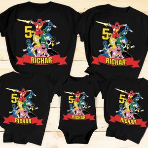 May include: Black t-shirts and a onesie featuring a colorful graphic of Power Rangers with the number 5 and the name "RICHAR" on a red banner. The Power Rangers are in various action poses.
