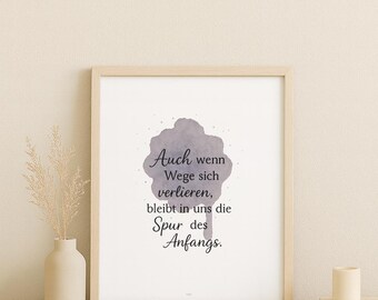 May include: A framed print with a light wood frame. The print features a watercolor-style design with the German text "Auch wenn Wege sich verlieren, bleibt in uns die Spur des Anfangs." A small vase with dried flowers is to the left.