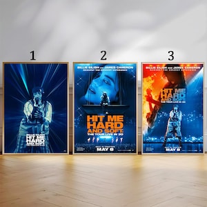 Può includere: Tre poster incorniciati con Billie Eilish. I poster presentano uno schema di colori blu e arancione con il testo "HIT ME HARD AND SOFT" e "THE TOUR LIVE IN 3D". I poster includono anche la data "MAY 8".