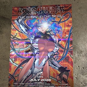 May include: A poster for "The Ghost in the Shell" anime. It features a futuristic female character with blue hair and metallic clothing. The poster has Japanese text at the top and the text "SARU JULY 2026" at the bottom. The background is a mix of red, orange, and yellow.