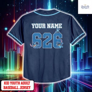 A dark blue baseball jersey with the text "YOUR NAME" and the number "626" printed on it, along with a cartoon character. The jersey appears to be a custom-made item for a child or young adult.