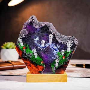 May include: A decorative resin sculpture featuring a starry night sky with white spirit figures and green mossy terrain. The sculpture is mounted on a wooden base and has a unique, irregular shape with a purple and orange color scheme.