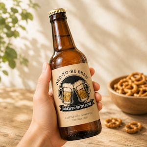 以下が含まれることがあります： DAD-TO-BE BREW、BREWED WITH LOVE、A LITTLE ONE IS BREWING、VINTAGE 2027という文字が書かれた茶色のラベルが付いた茶色のガラス製ビール瓶。ラベルには、黄金色の液体が入った2つのビールジョッキが乾杯しているイラストが描かれています。