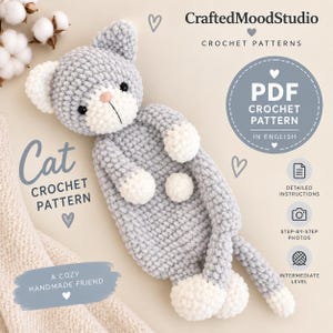 Può includere: Un giocattolo a forma di gatto lavorato all'uncinetto in grigio e bianco con una consistenza morbida e pelosa. Il gatto ha una testa rotonda, orecchie piccole e un muso bianco con un naso rosa. Il testo include CraftedMoodStudio, PDF CROCHET PATTERN e A COZY HANDMADE FRIEND.