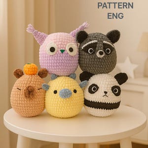Pode incluir: Uma coleção de brinquedos de animais de crochê feitos à mão, incluindo uma coruja, um guaxinim, um panda, um urso e um pintinho. Os brinquedos são em várias cores, como rosa, cinza, branco, amarelo e marrom. O texto "PDF CROCHET PATTERN ENG" é visível.