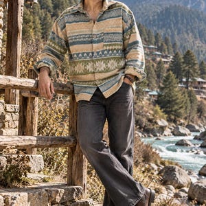 Può includere: Una camicia a maniche lunghe con bottoni caratterizzata da un motivo geometrico multicolore nei toni del beige, verde salvia e blu, abbinata a jeans in denim grigio antracite e stivali in pelle marrone scuro per un outfit coordinato.