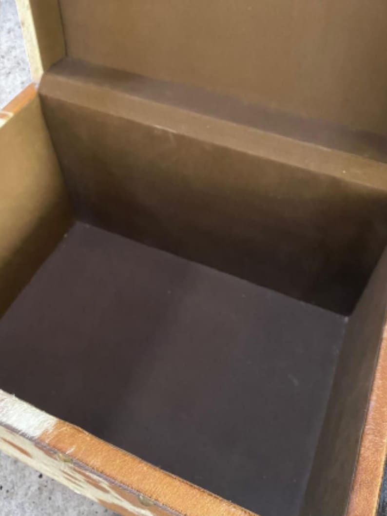 K&ouml;nnte beinhalten: Eine offene, rechteckige Aufbewahrungsbox mit braunem Innenraum und hellbraunem &Auml;u&szlig;eren. Die Box hat einen dunkelbraunen Innenboden und ein hellbraunes &Auml;u&szlig;eres mit einem gemusterten Design. Die Box ist aus Holz.