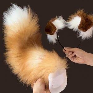 May include: A set consisting of a long, fluffy faux fur tail with a white tip and a brown and white gradient, and a matching headband featuring two plush, rounded animal ears with brown outer edges and white inner fur accents.