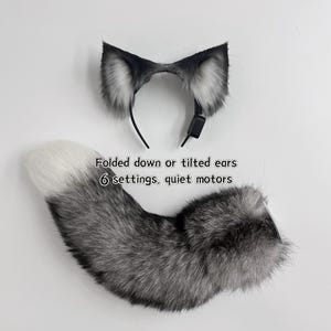 Könnte beinhalten: Ein Set aus Kunstfell-Tierohren auf einem Haarreif und einem passenden langen Kunstfellschwanz. Die Ohren sind schwarz-weiß und verfügen über einen Motor. Der Text auf dem Bild lautet: Folded down or tilted ears, 6 settings, quiet motors.