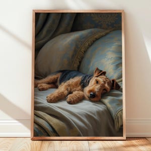 May include: A framed print of a dog resting on a bed. The dog has brown and black fur and is lying on a light blue blanket. The pillows behind the dog are light blue with a gold floral pattern. The frame is made of wood.