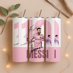 May include: Three white stainless steel tumblers with pink accents and a silver straw. Each tumbler features a photo of Lionel Messi, his signature, and the text "MESSI". The number "10" is also visible.