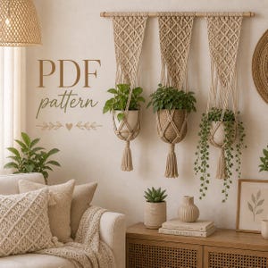 May include: Three macrame plant hangers with potted plants suspended from a wooden rod. The beige hangers have a diamond pattern and tassels. The image includes the text "PDF pattern". The room has a neutral colour palette with a sofa and wooden furniture.