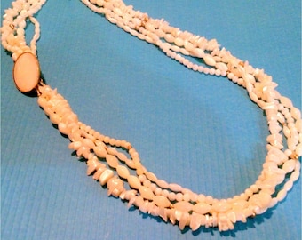 May include: A multi-strand necklace made of white shell beads. The necklace has a gold clasp.