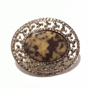 Broche vintage de inspiração vitoriana com moldura dourada e centro marrom manchado