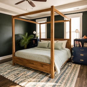 Könnte beinhalten: Ein hölzernes Himmelbett mit einer hellgrünen Bettdecke und Kissen. Der Bettrahmen ist aus hellfarbigem Holz gefertigt. Der Raum hat dunkelgrüne Wände, einen gemusterten Teppich und einen Deckenventilator.