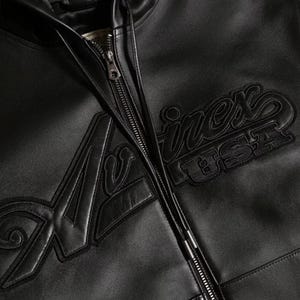 May include: Black leather jacket with a zip closure. The jacket features the embroidered word "A&shy;virex USA" in a stylized font on the front. The jacket has a classic design.