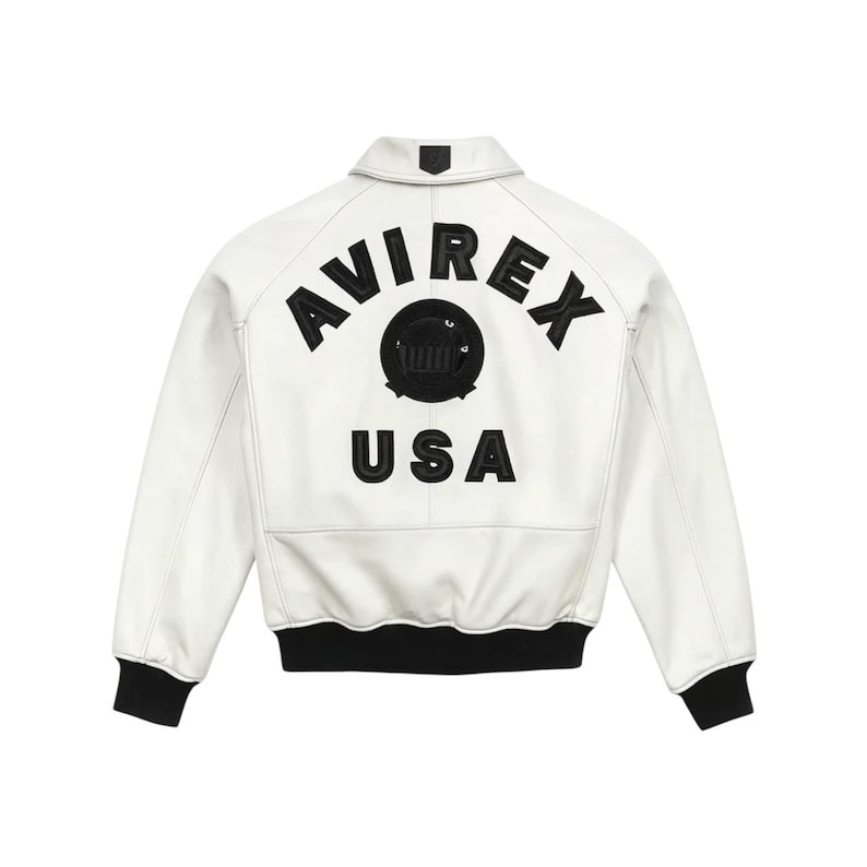 May include: White leather jacket with black ribbed cuffs and collar. The back features the embroidered text "AVIREX USA" above a circular emblem. A classic bomber jacket style.