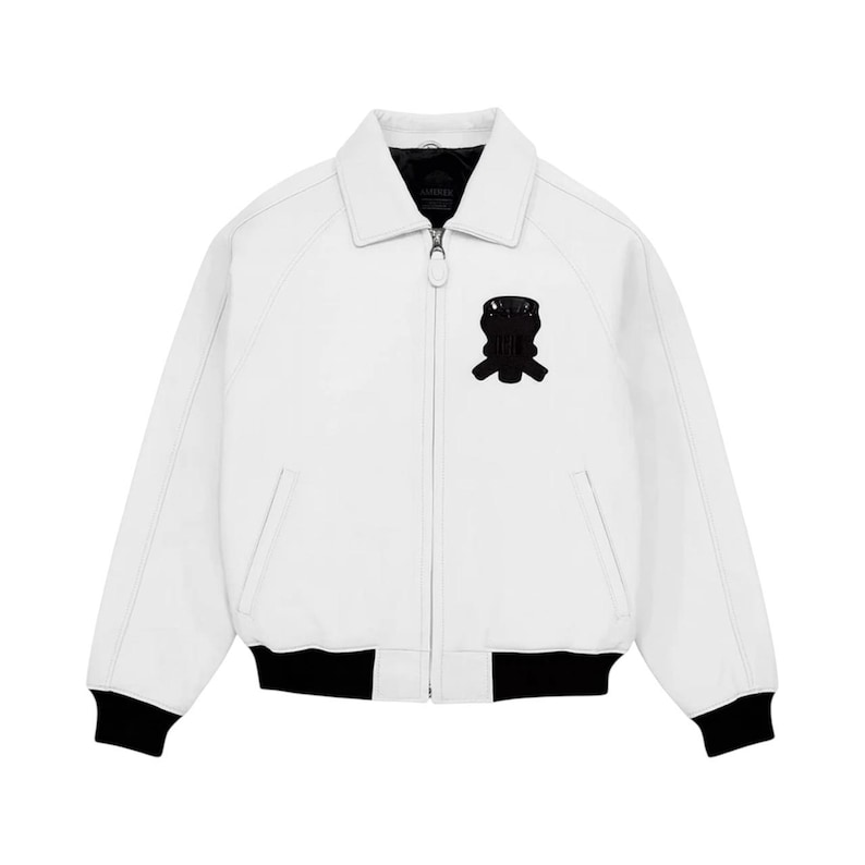 May include: A white bomber jacket with a black collar, cuffs, and a black emblem on the chest. The jacket has a zipper closure and two front pockets. The jacket is made of a smooth material.