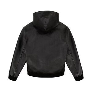 May include: A black leather jacket with a hood, seen from the rear. The jacket features long sleeves and a black ribbed hem and cuffs. The hood is a high, structured design. The jacket is crafted from smooth, matte leather.