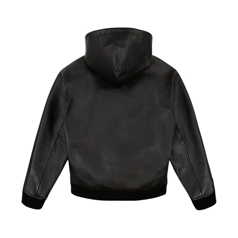 May include: A black leather jacket with a hood, seen from the rear. The jacket features long sleeves and a black ribbed hem and cuffs. The hood is a high, structured design. The jacket is crafted from smooth, matte leather.