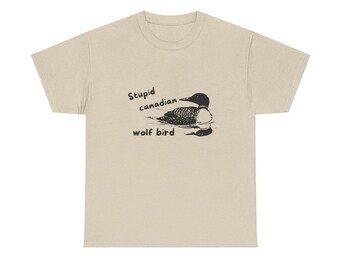 May include: Beige t-shirt with a black graphic of a loon and the text "Stupid canadian wolf bird". The graphic features the loon in the water. The shirt is made of a soft, comfortable material.