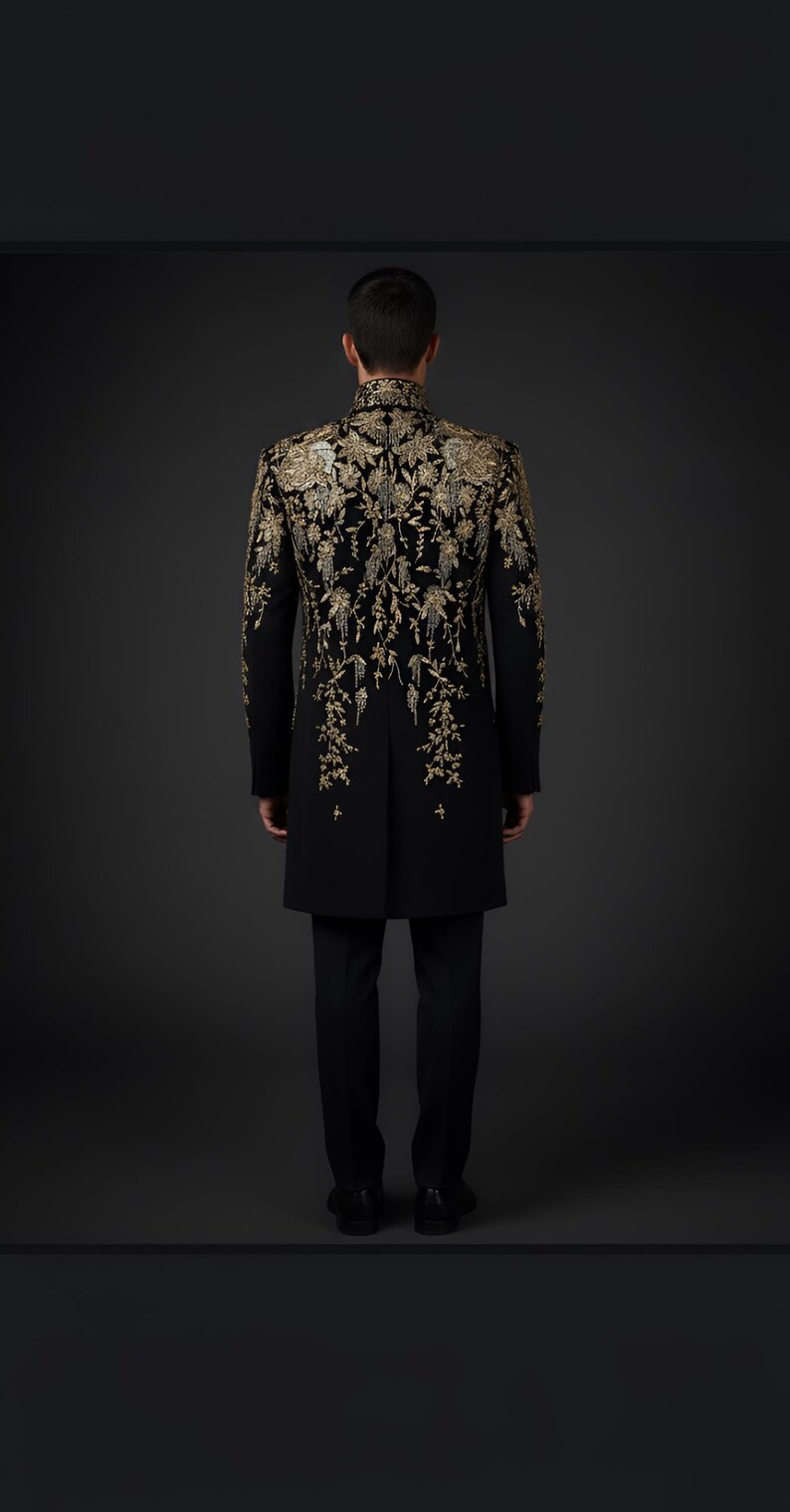 May include: A black formal coat with intricate gold embroidery. The design features floral patterns cascading down the back and sleeves. The coat is paired with black trousers, creating a sophisticated ensemble.