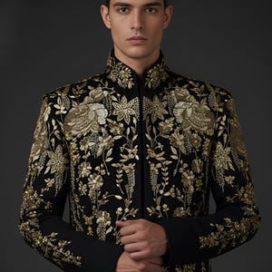May include: A black jacket with intricate gold floral embroidery. The jacket features a mandarin collar and long sleeves. A gold headband complements the jacket's design. The garment is a formal wear item.