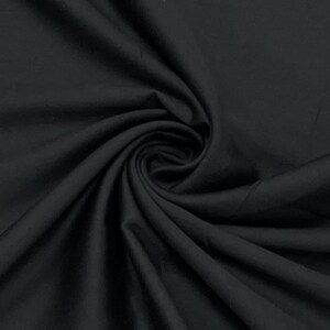 May include: A close-up shot of black fabric with visible folds and a swirling pattern. The fabric appears to be smooth and opaque, with a slight sheen. The image highlights the texture and depth of the material.