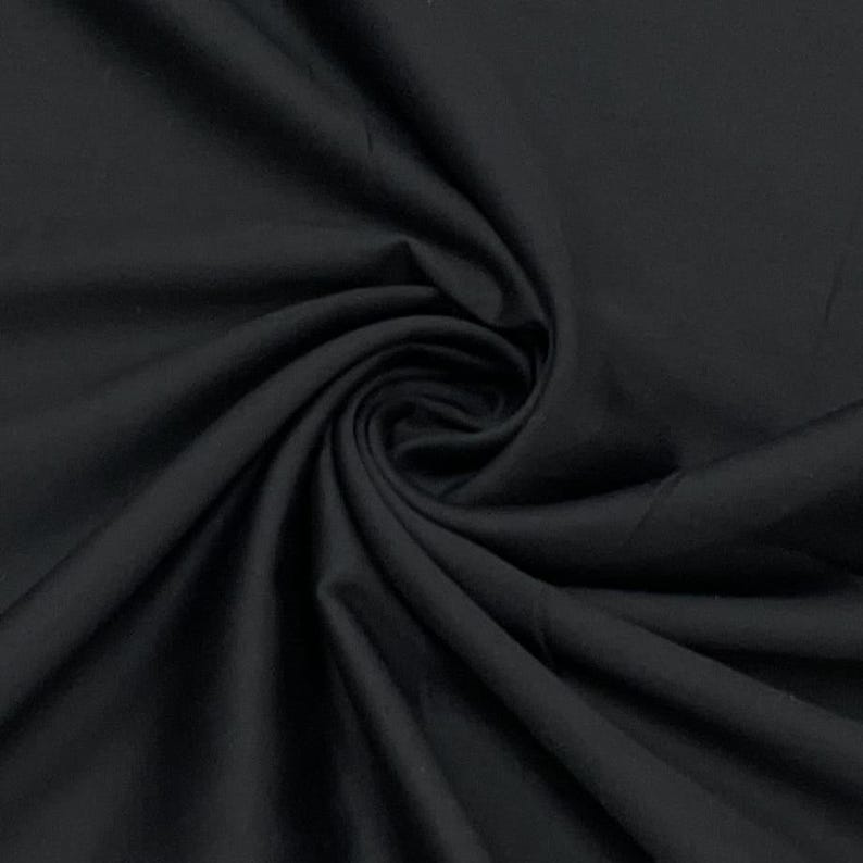 May include: A close-up shot of black fabric with visible folds and a swirling pattern. The fabric appears to be smooth and opaque, with a slight sheen. The image highlights the texture and depth of the material.