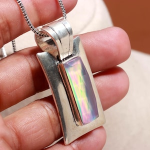 May include: Silver pendant necklace featuring a rectangular iridescent gemstone. The pendant has a silver frame and is suspended from a delicate chain. The gemstone displays a spectrum of colors, including pink, green, and yellow.
