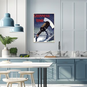 May include: A framed vintage Guinness Time advertisement. The poster features a large Guinness bottle being poured by a small figure. The words "Guinness Time" are in red at the top. The artwork has a blue and white color scheme.