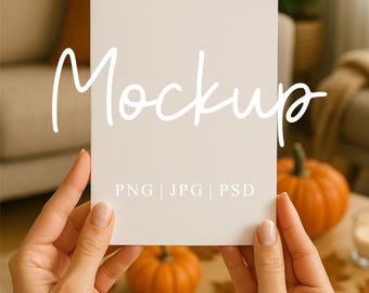 May include: A blank white card held by hands, with the word "Mockup" in cursive script. The card has "PNG | JPG | PSD" printed below. Pumpkins and fall leaves are on a table. The Mockup Studio UK is printed at the bottom.