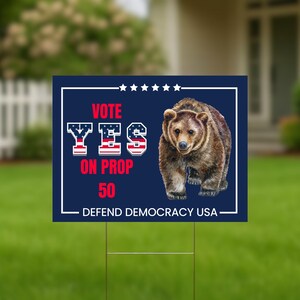 May include: A rectangular yard sign with a dark blue background, white border, and a brown bear illustration. The sign reads "VOTE YES ON PROP 50" in red and white text. The bottom of the sign says "DEFEND DEMOCRACY USA".